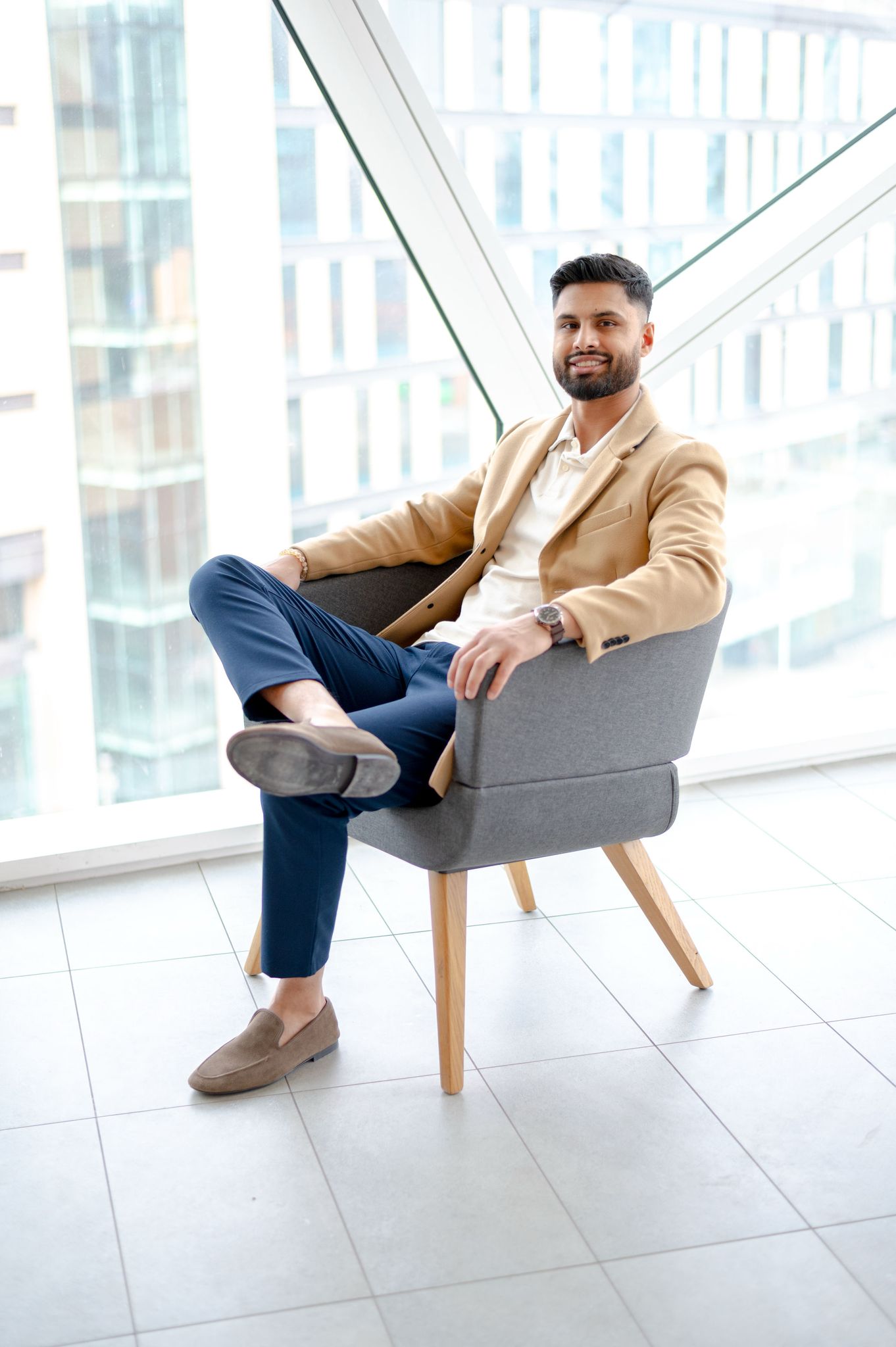 Sukh Gill, Calgary REALTOR® with Real Broker, seated with the downtown Calgary skyline behind him